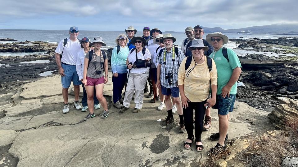 Grupo de viajeros sobre rocas volcánicas junto al mar