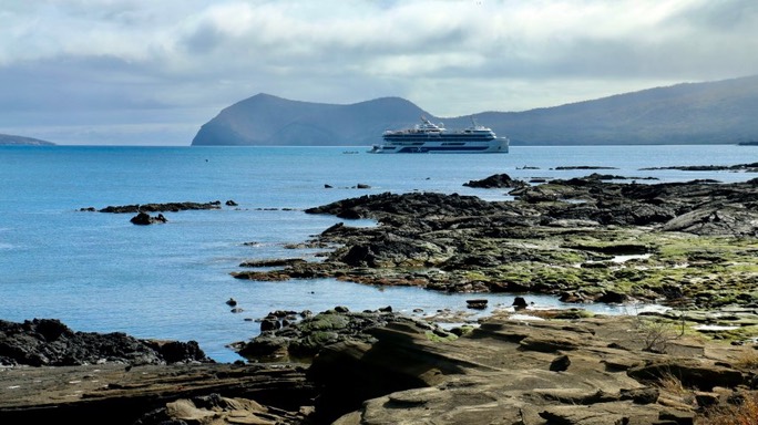 Costa rocosa de Galápagos con el mar en calma y una isla al fondo