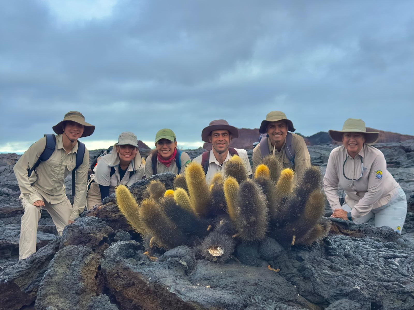 Guías con uniforme sonriendo junto a un cactus de lava