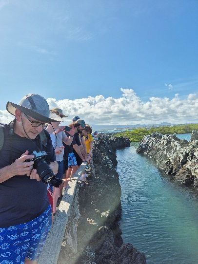 Viajeros fotografiando el canal de Las Tintoreras entre rocas de lava