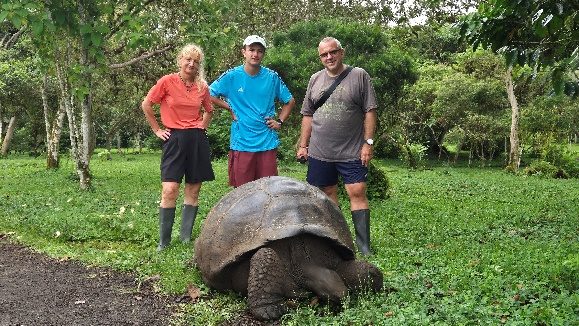 Tres viajeros junto a una tortuga gigante en la parte alta de Santa Cruz