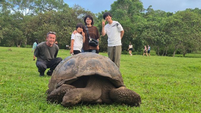 Viajeros junto a una tortuga gigante en un prado de la parte alta de Santa Cruz
